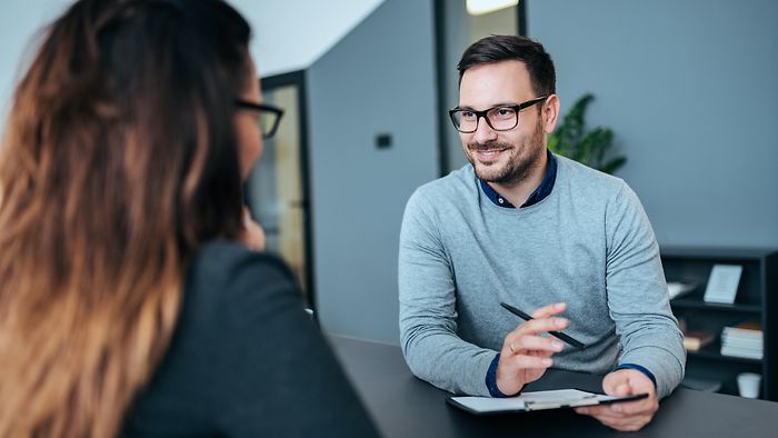 Bewerber im grauen Pullover im Gespräch mit Recruiterin