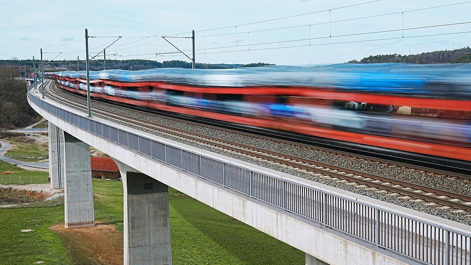 Train with cars drives fast over a bridge