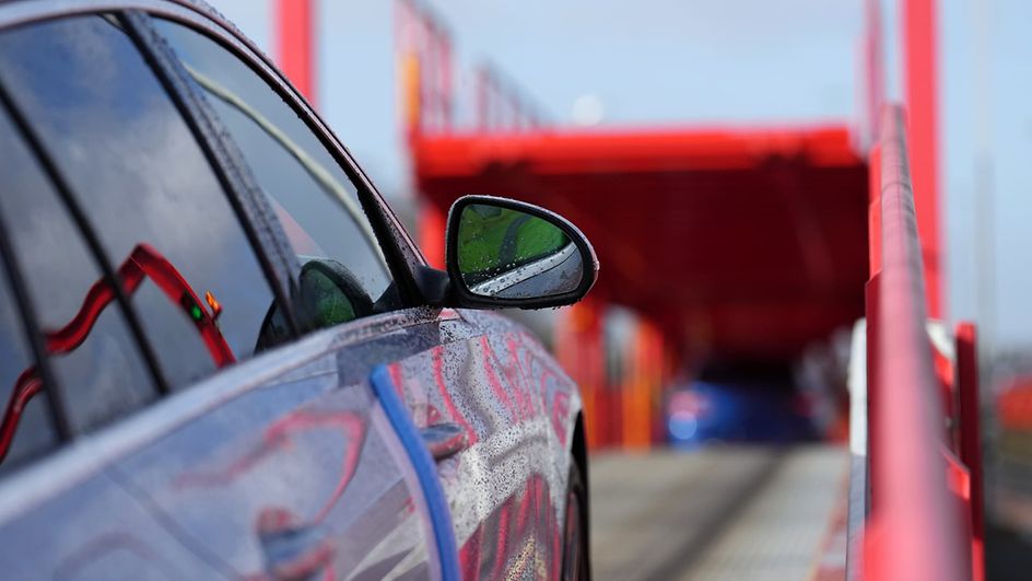 A car drives up a ramp onto a car carrier wagon