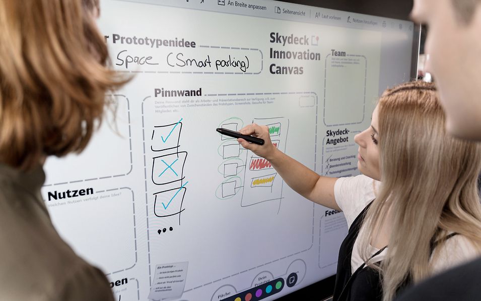Frau zeigt Kollegen Präsentation am Smartboard