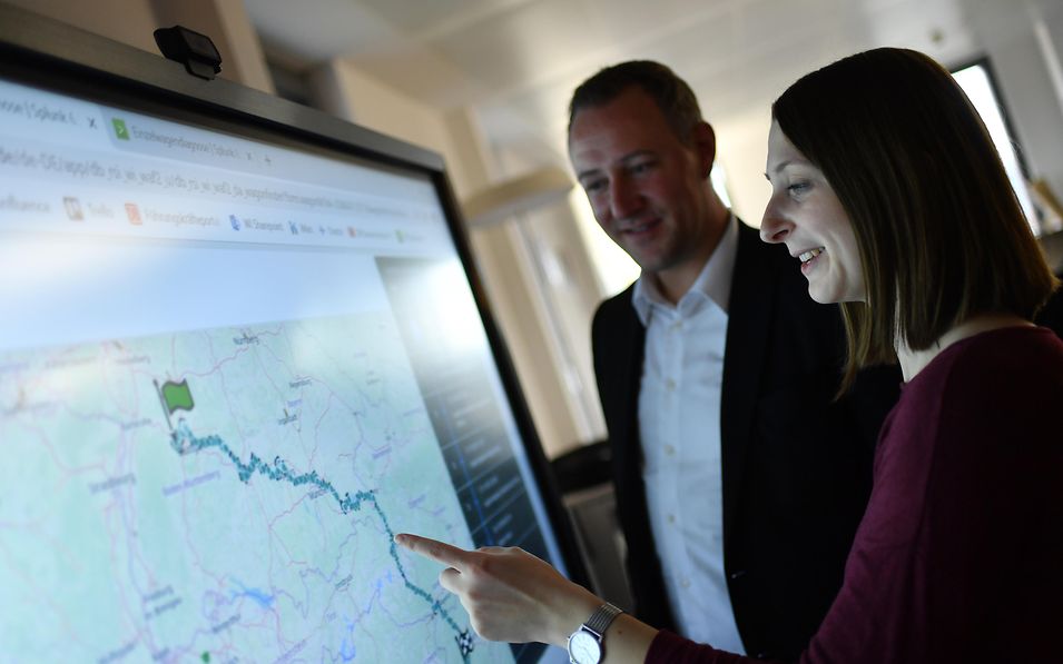 Quelle: DB Cargo / Oliver Lang Zwei Mitarbeiter betrachten die Streckenführung auf einem Smartboard