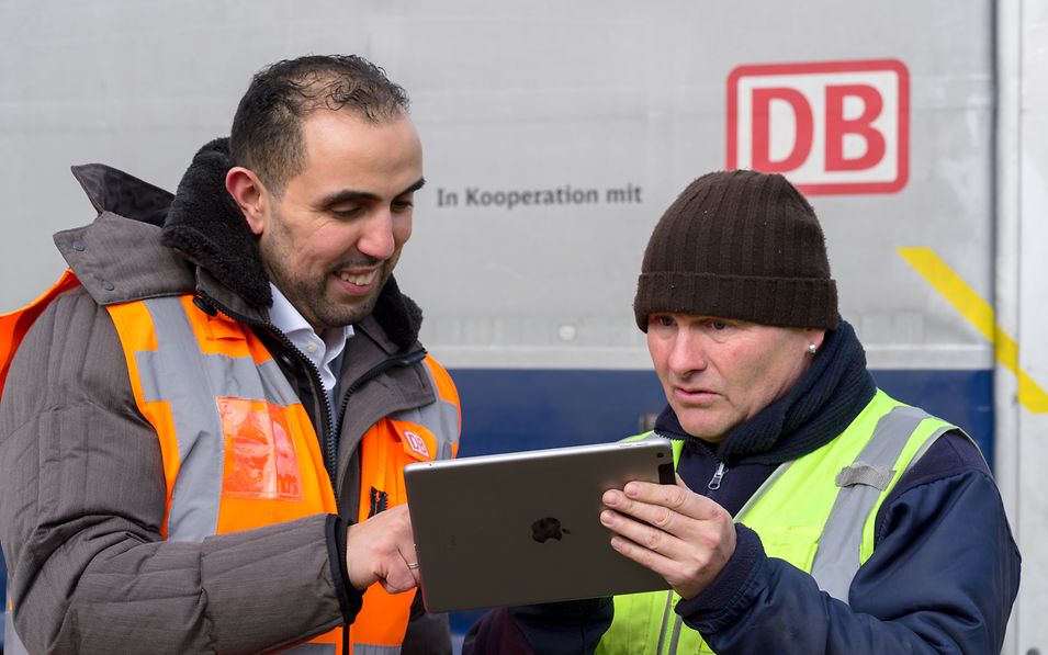 Zwei Mitarbeiter schauen auf ein mobiles Endgerät