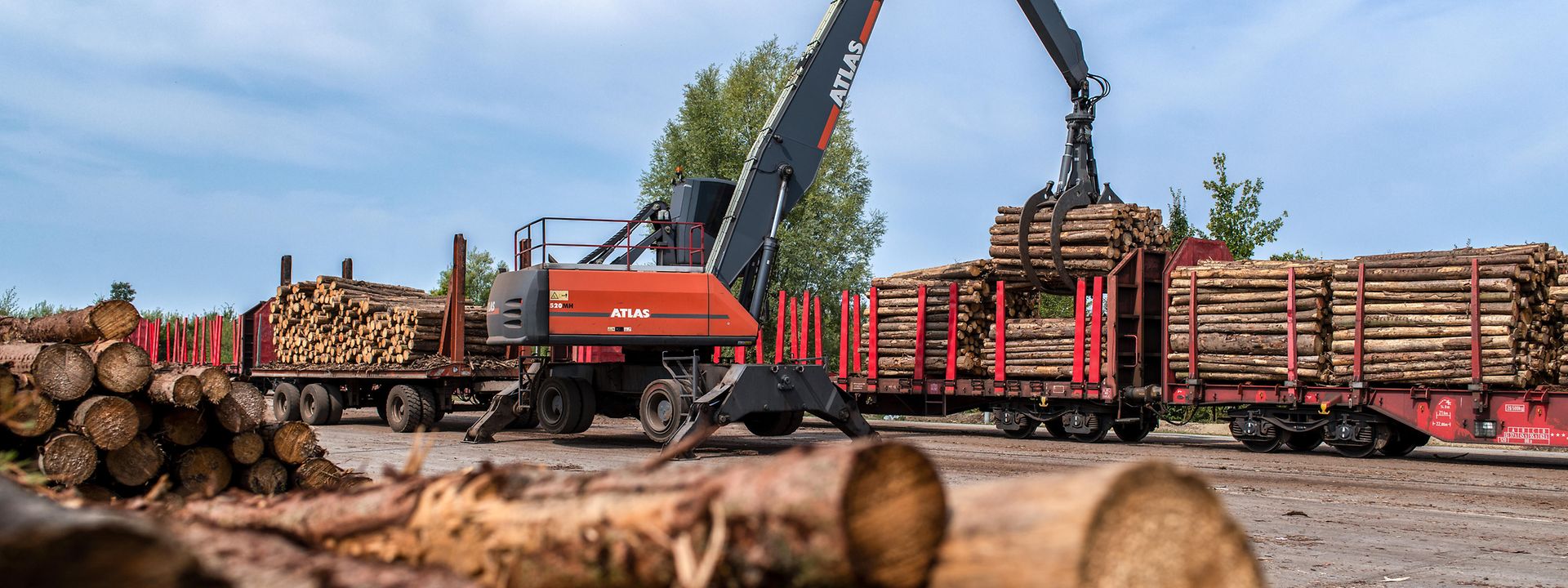 A crane loads raw timber onto a stanchion wagon
