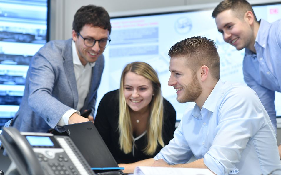 Four people in business dress working together on a computer