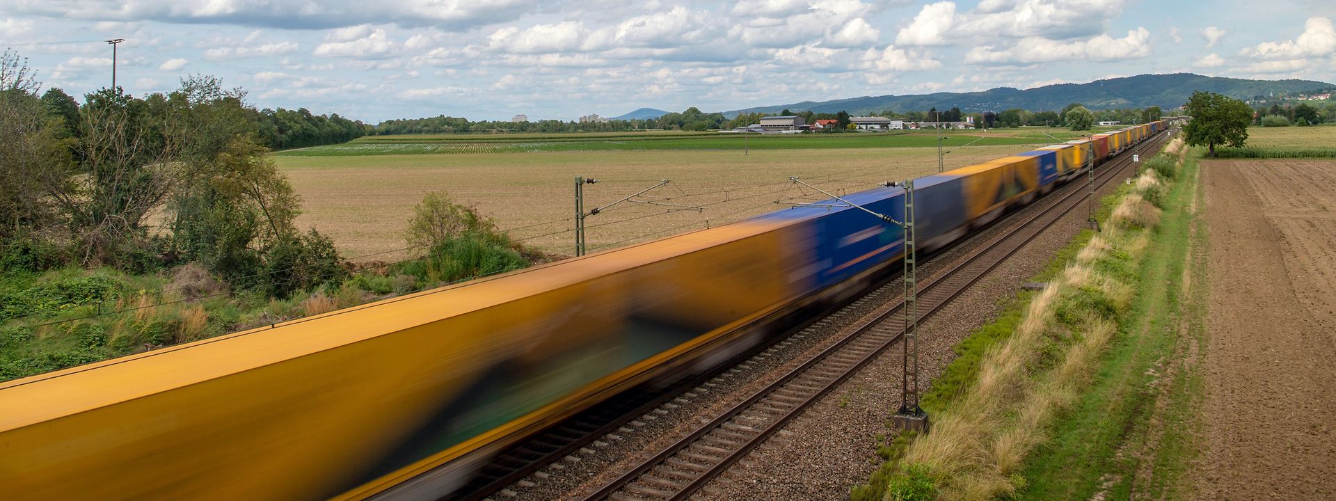 A yellow train travels through the countryside