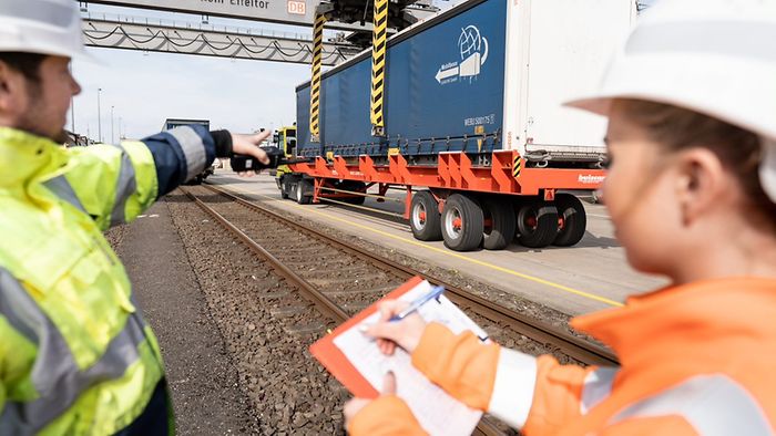 Zwei Mitarbeitende besprechen die Verladung eines LKWs auf die Schiene 