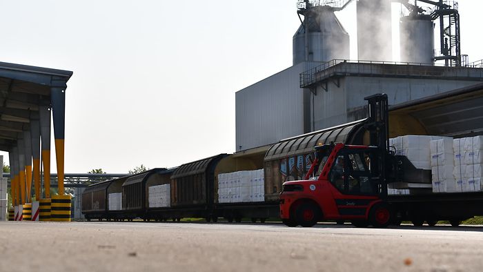 Forklift loading pulp onto an open train at a plant