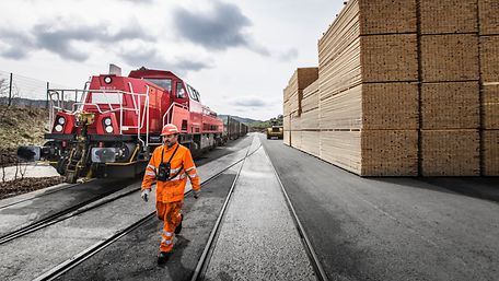 DB employee between a locomotive and stacks of timber 